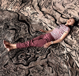 Sherry Xiang lying on the ground, AAL2022 This Land artist